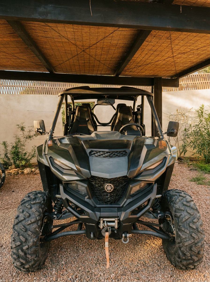Front view of the black and orange Yamaha Wolverine RMAX guest buggy beneath the shaded carport at Can Serenico