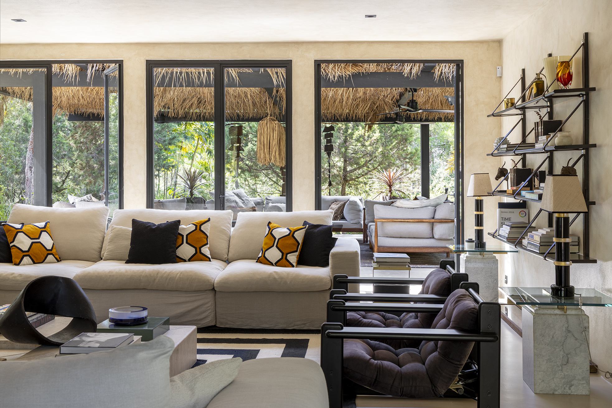 Front view of the living room sofa facing the pergola and garden through steel-framed doors
