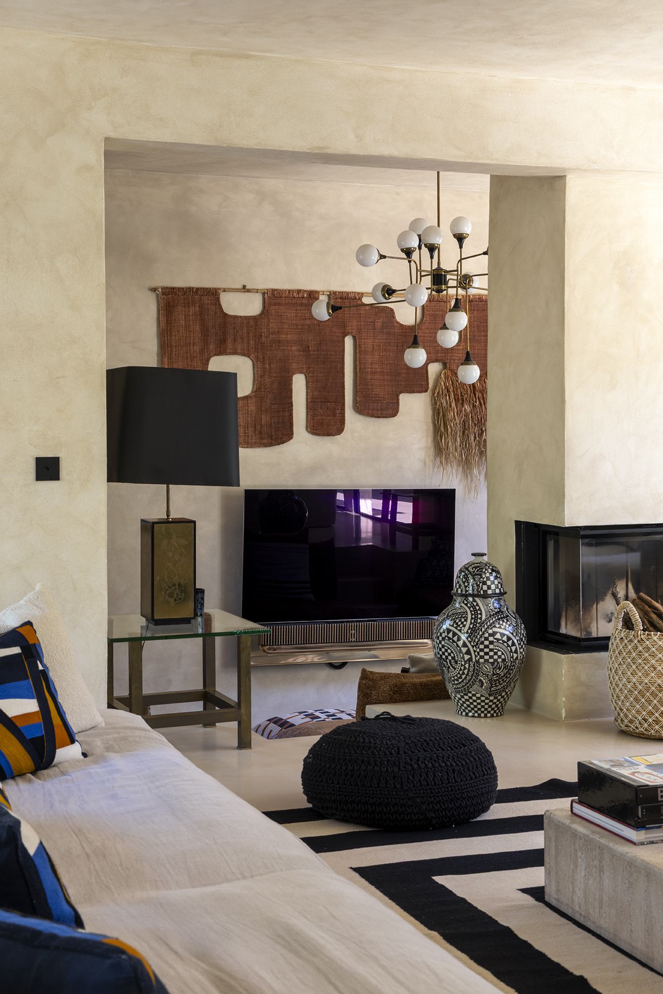 Close view of the living room fireplace, chandelier and woven textile above the television