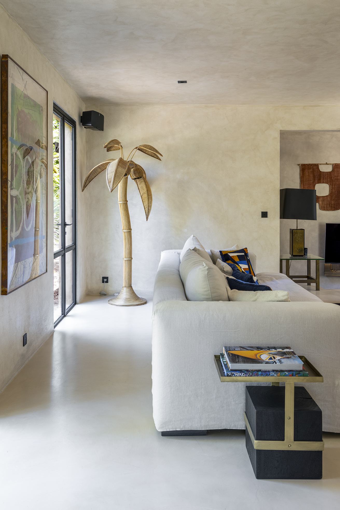 Side view of the living room with woven palm floor lamp and pale linen sofa