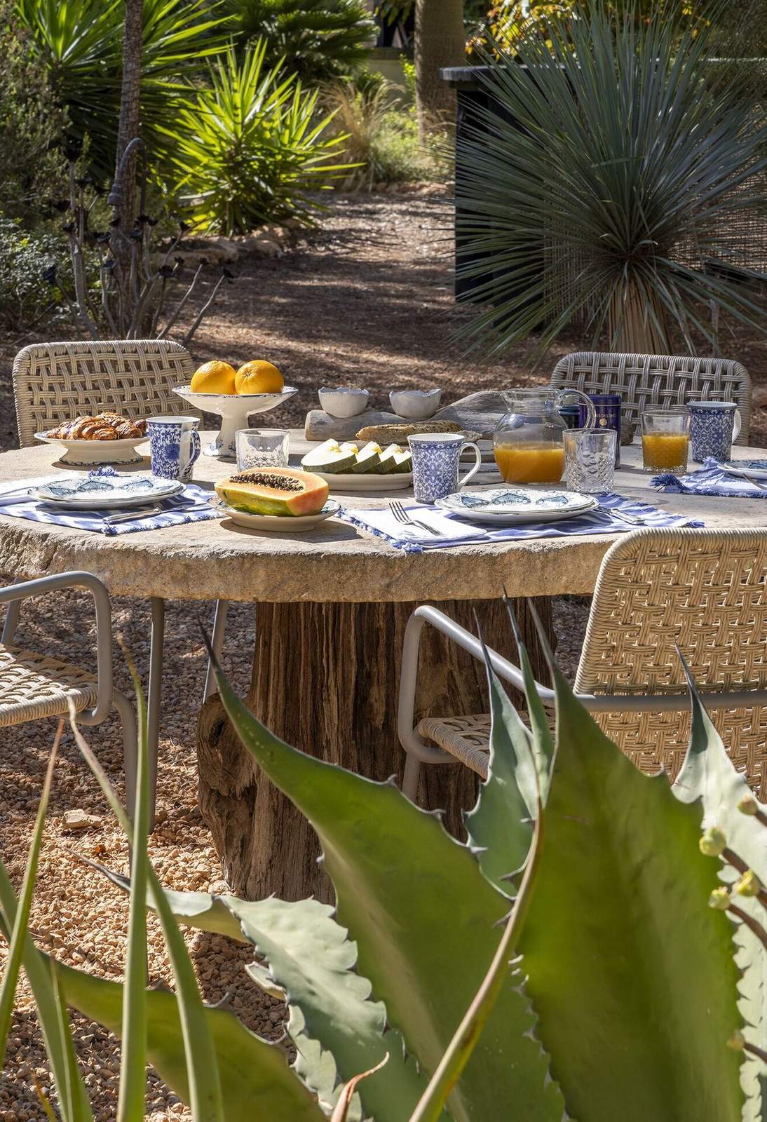 Round stone breakfast table set with blue and white ceramics, papaya, oranges and orange juice