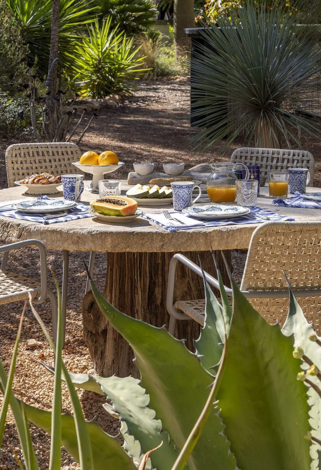 Round stone breakfast table set with blue and white ceramics, papaya, oranges and orange juice