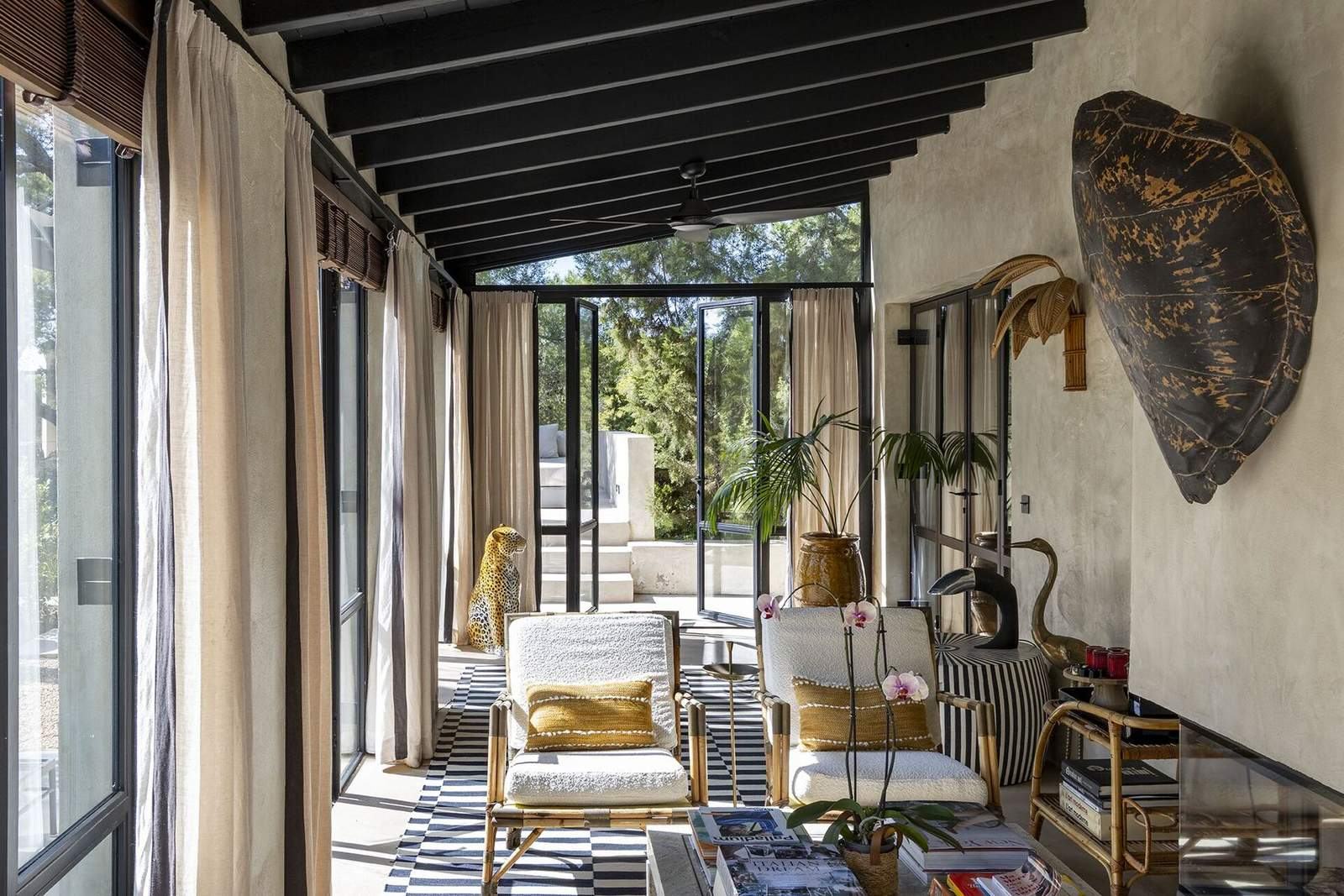 Long sunroom with bamboo chairs, striped rug and steel doors to the garden