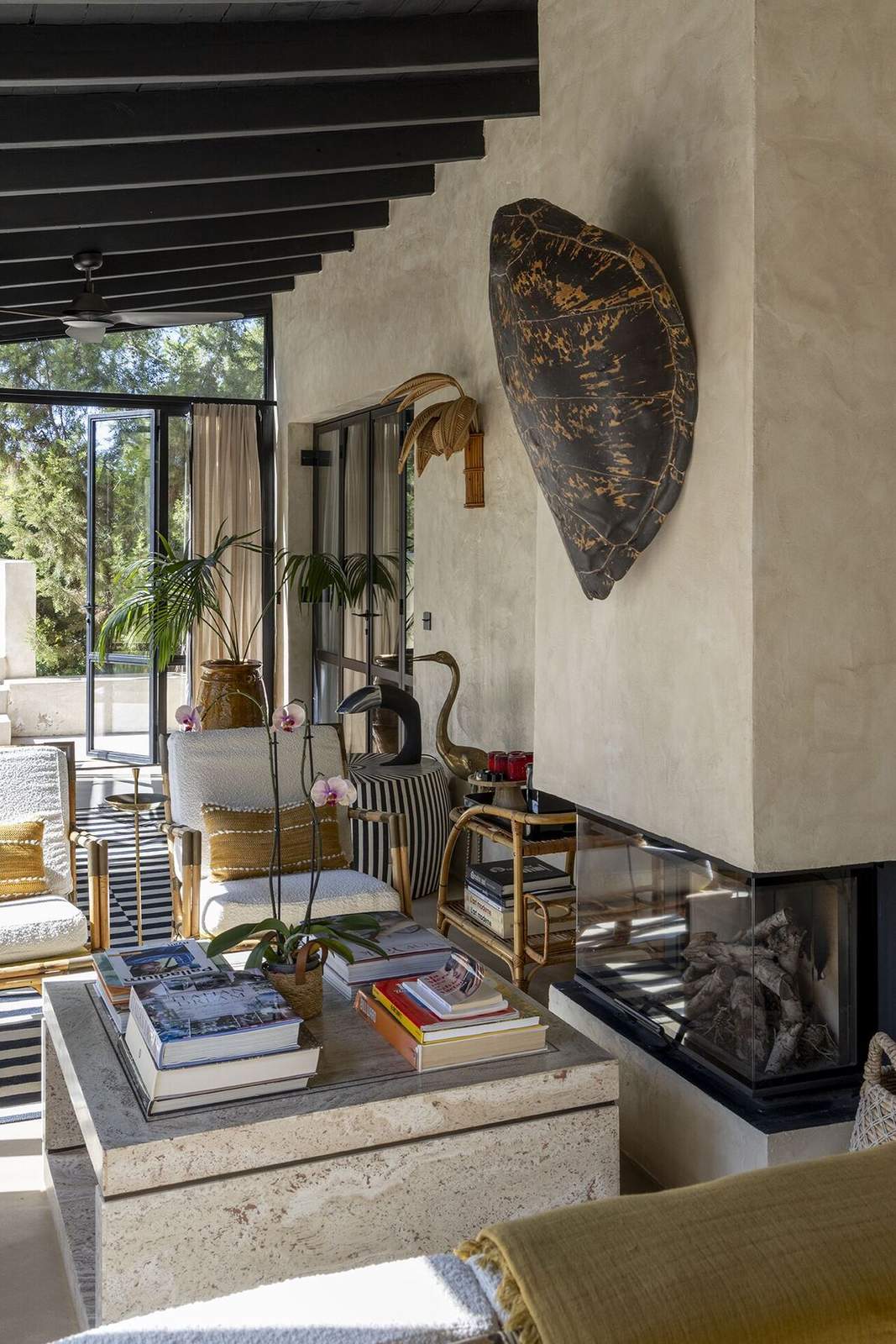 Travertine coffee table beside a glass-front fireplace and turtle shell