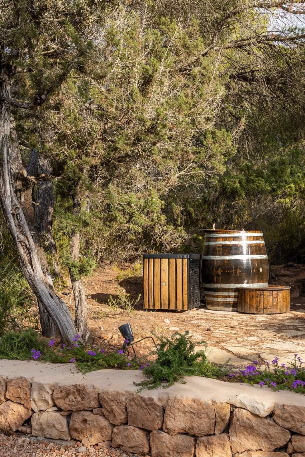 Oak ice plunge barrels and cold shower set on a stone terrace among junipers
