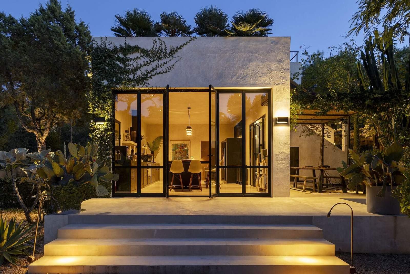 Kitchen pavilion glowing at dusk among cactus and palms