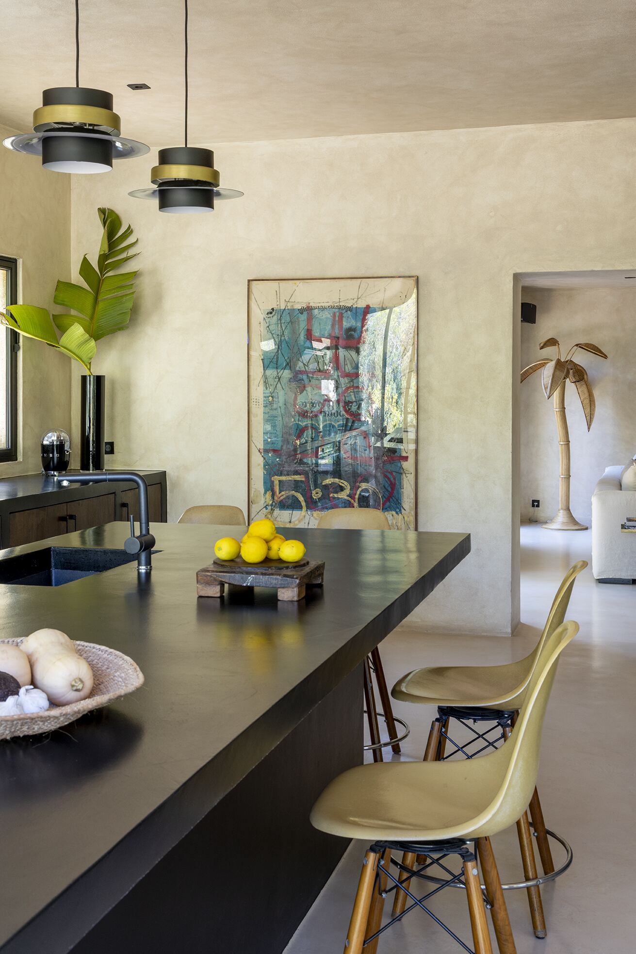 Black concrete kitchen island with lemons, pendant lights and Eames stools