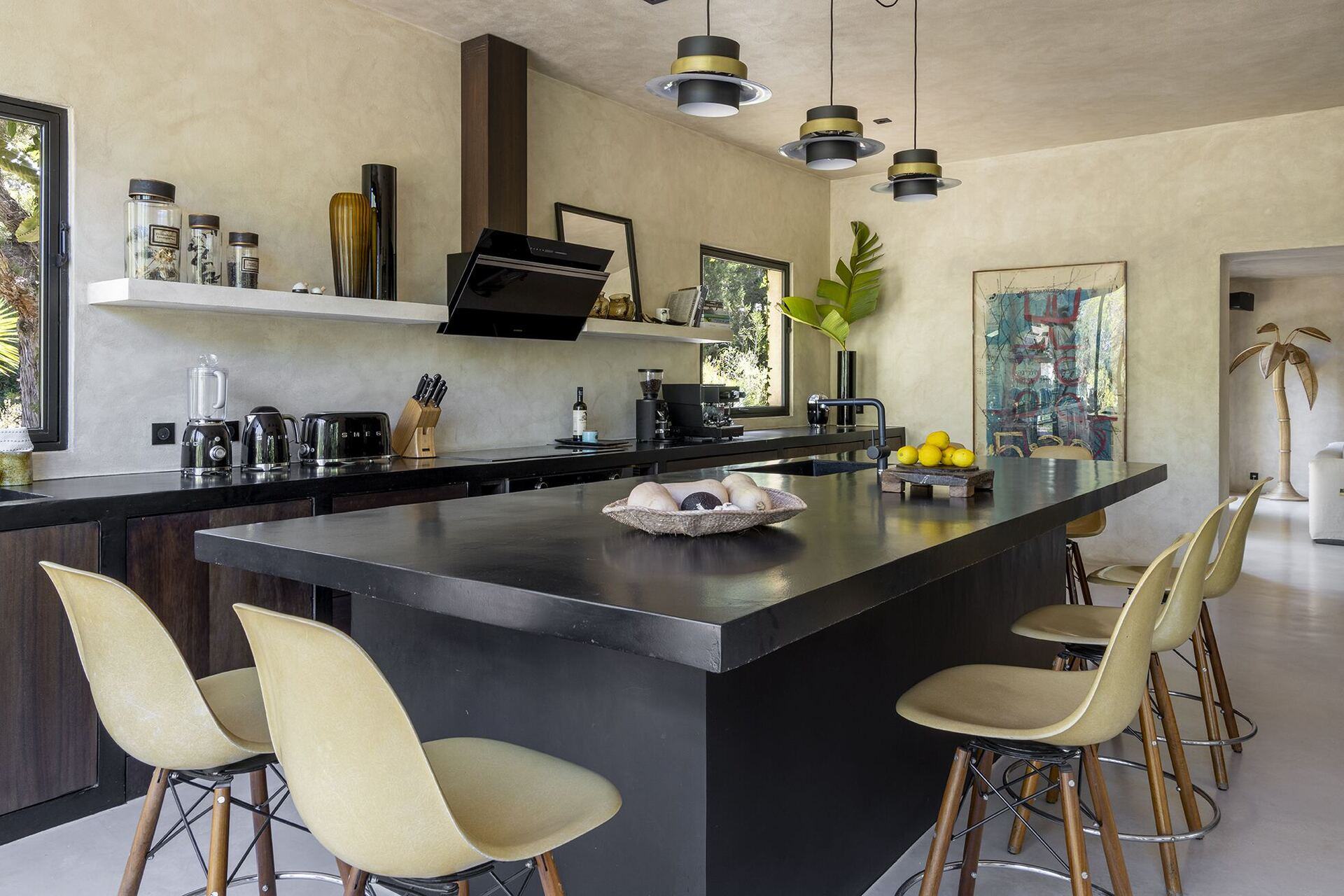 Wide view across the kitchen island, stools, pendants and artwork