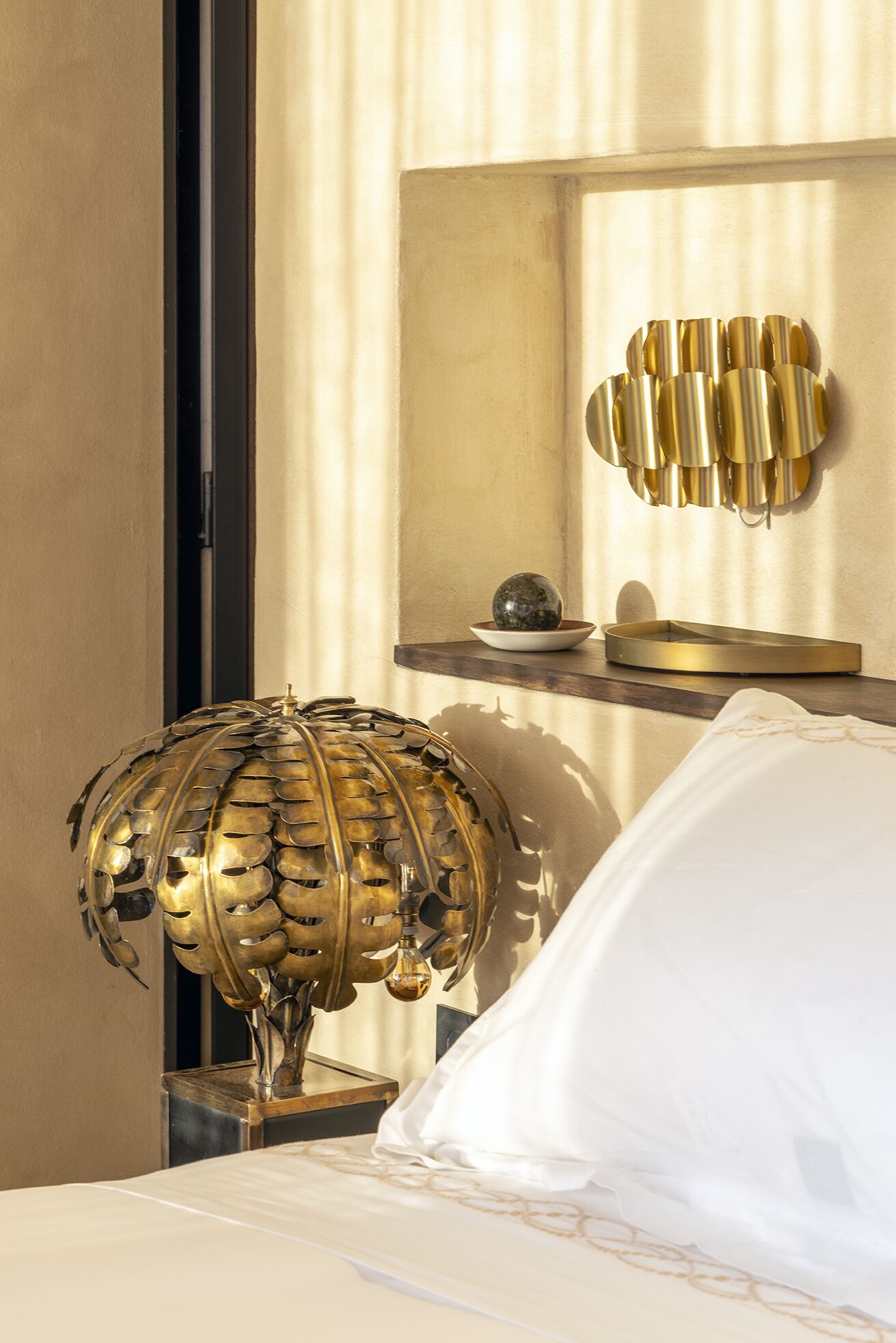 Brass palm lamp and fluted wall sconce in a hand-formed niche