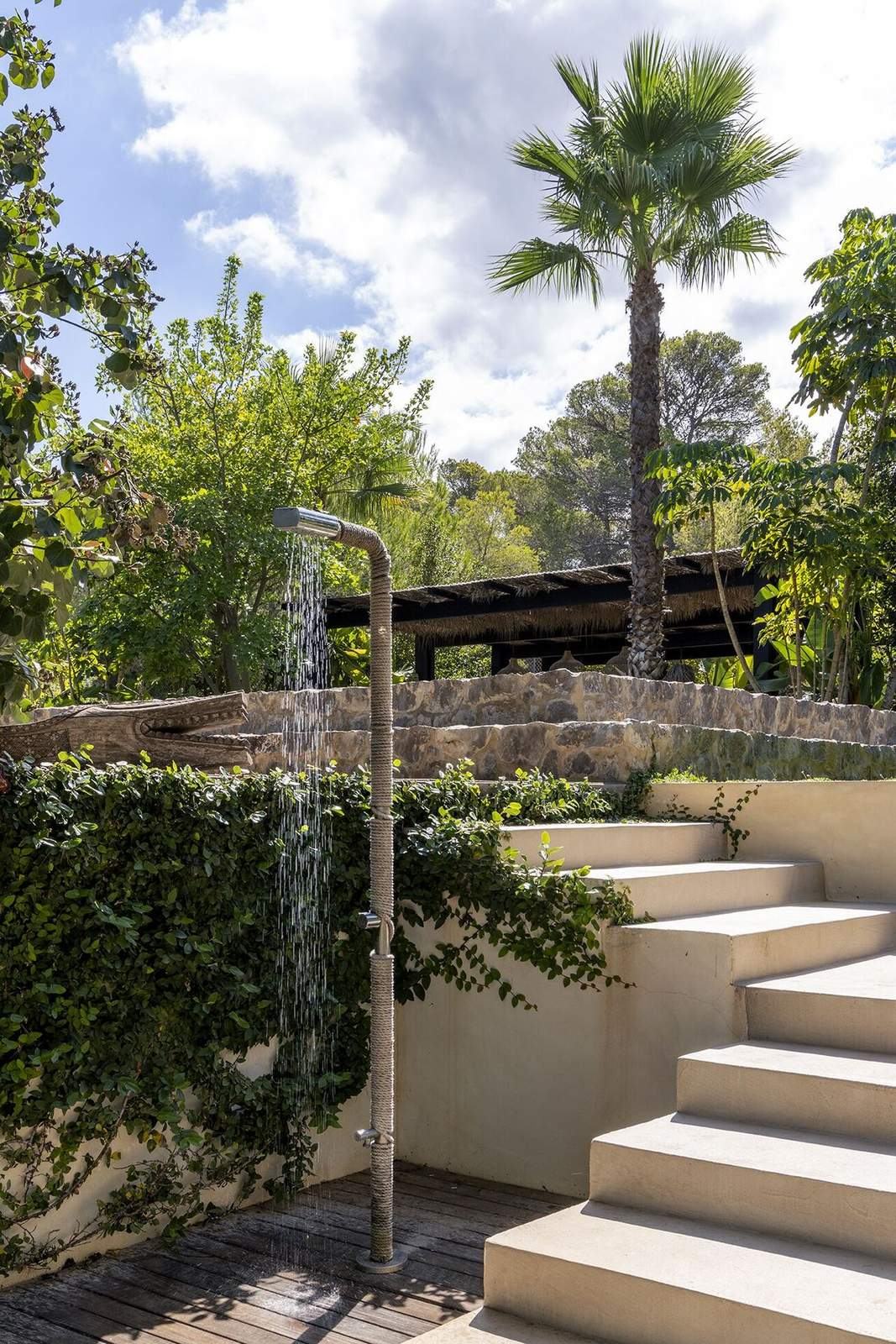 Rope-wrapped outdoor shower beside white steps leading up from the pool deck