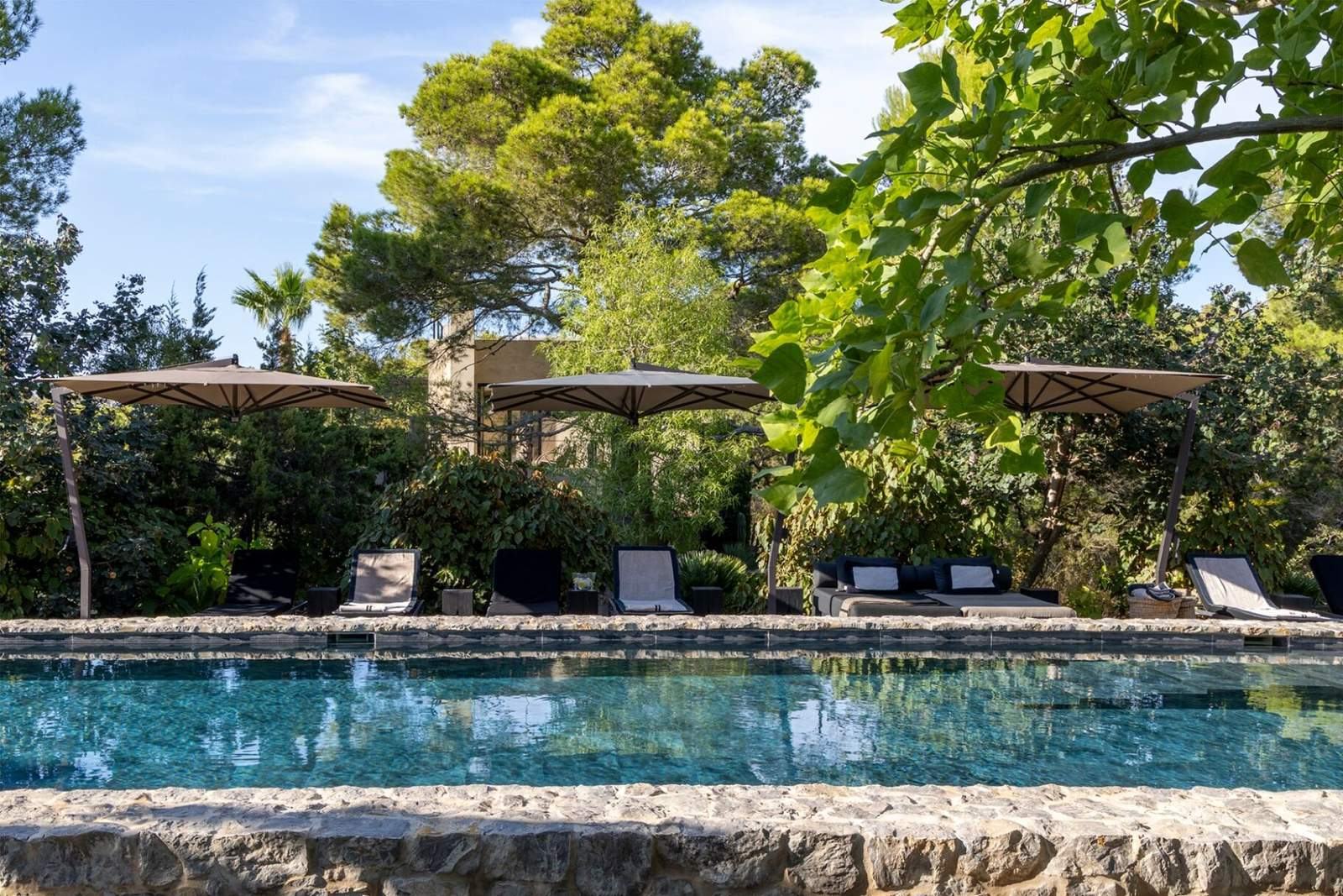 Row of loungers under three parasols beside the long pool