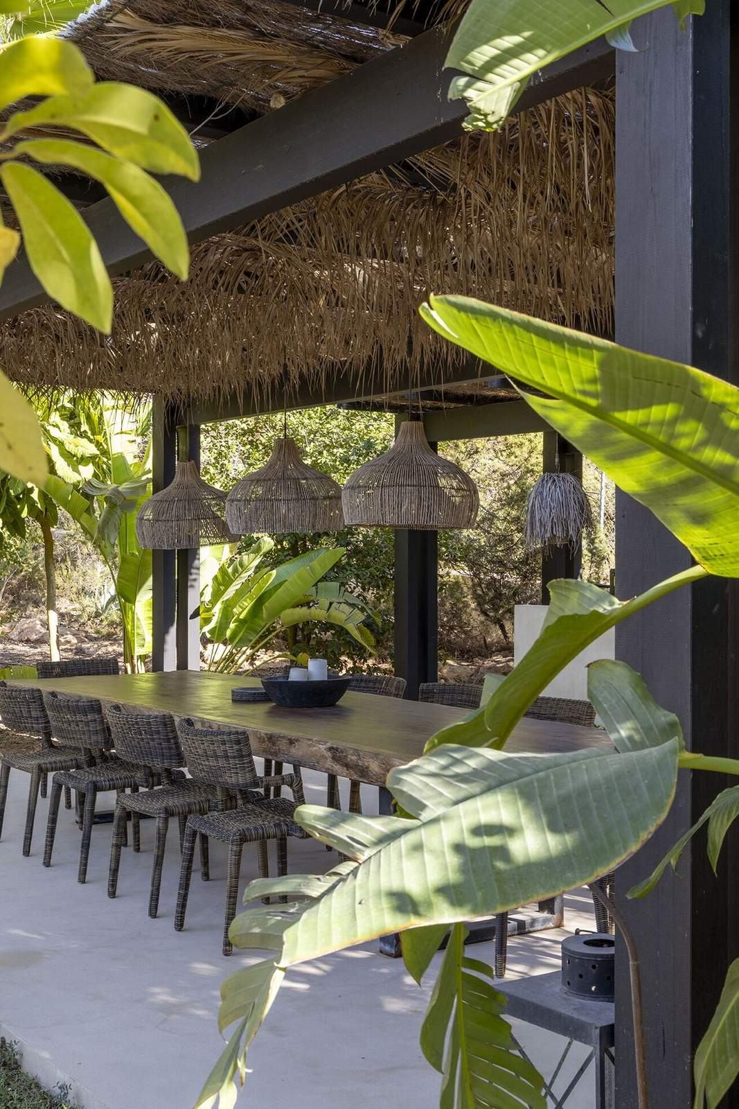 Woven lanterns and long dining table beneath the thatched pool pavilion