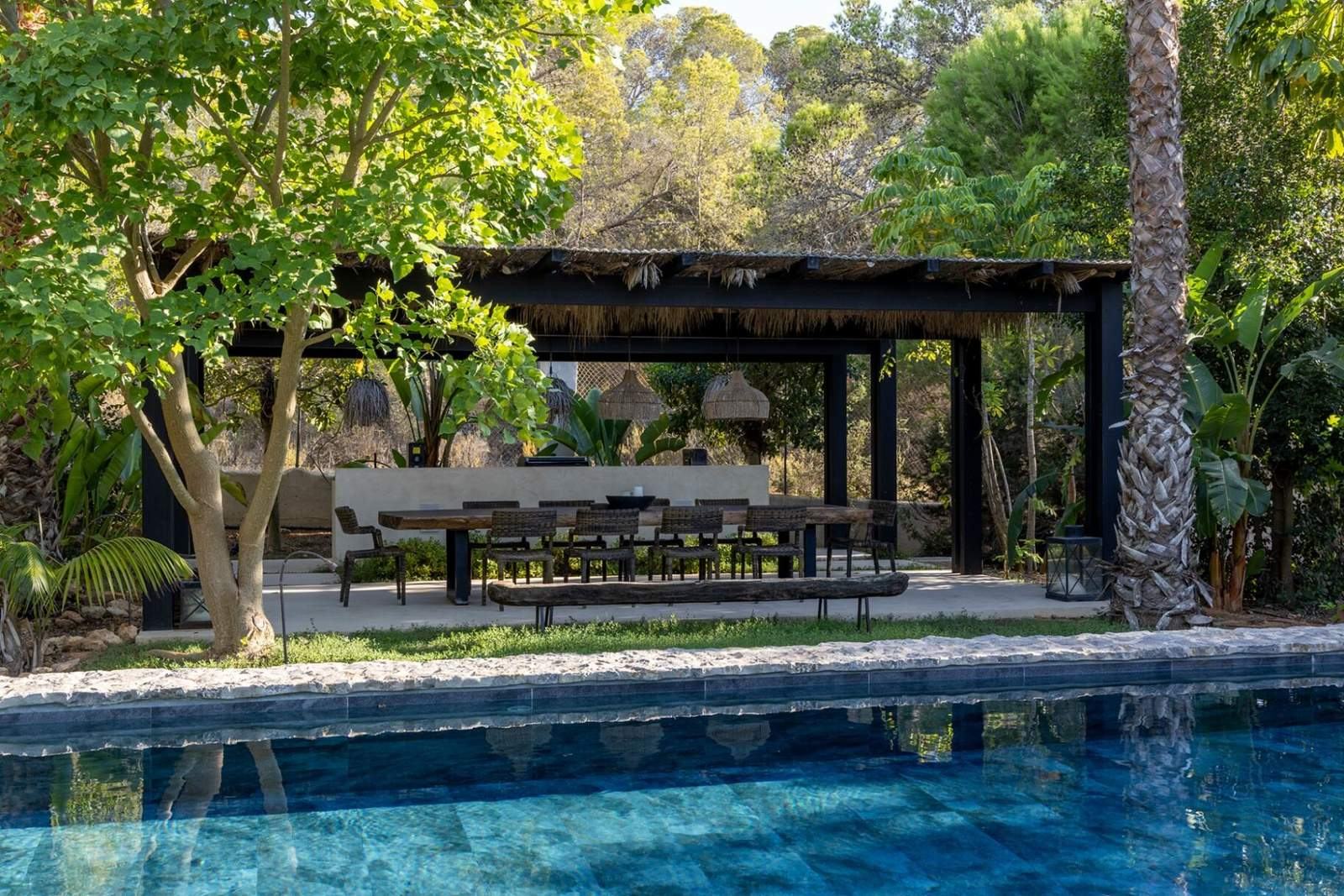 Poolside pavilion with long dining table seen across the water