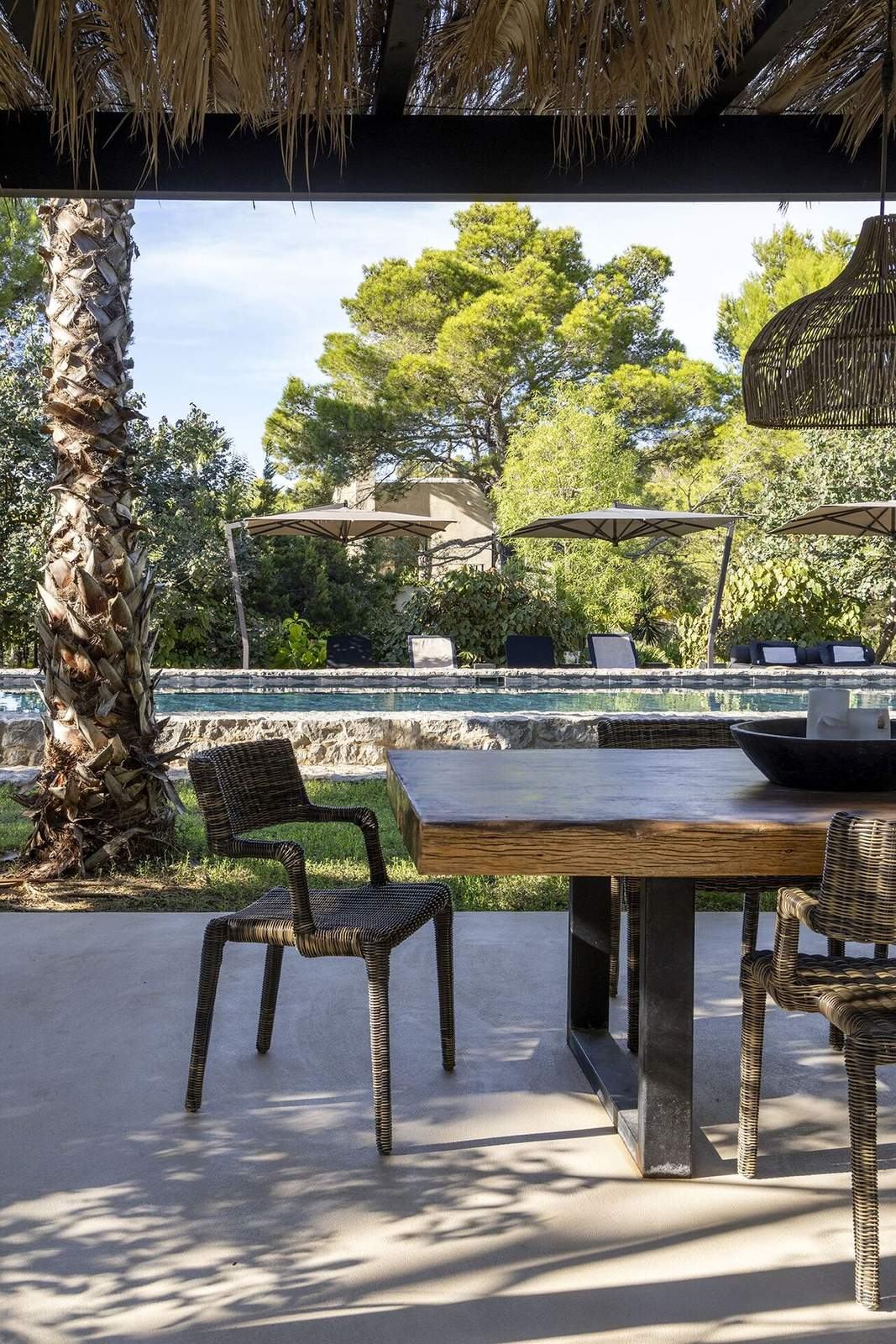 View from the shaded pavilion across the pool to loungers and parasols