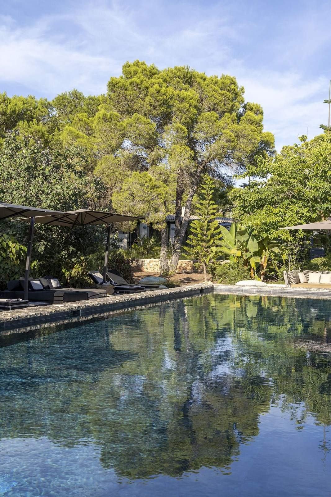 Long stone-edged pool reflecting pines and bright morning sky