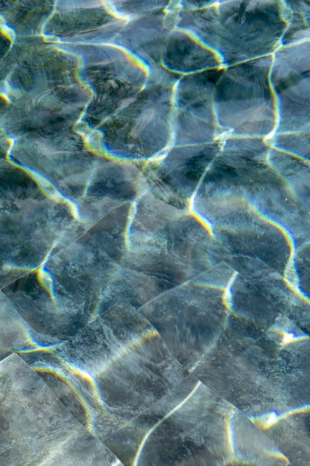 Sunlight refracting across the tiled pool floor