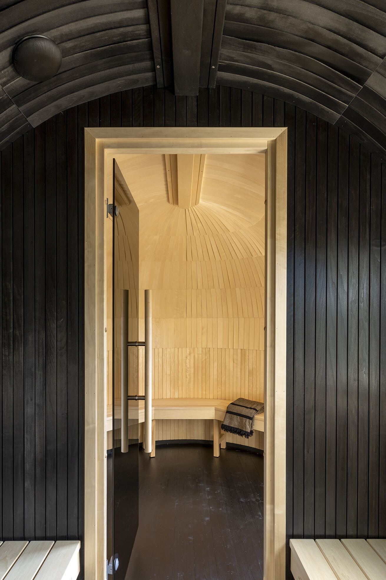 Doorway from the dark outer chamber into the pale-wood inner sauna