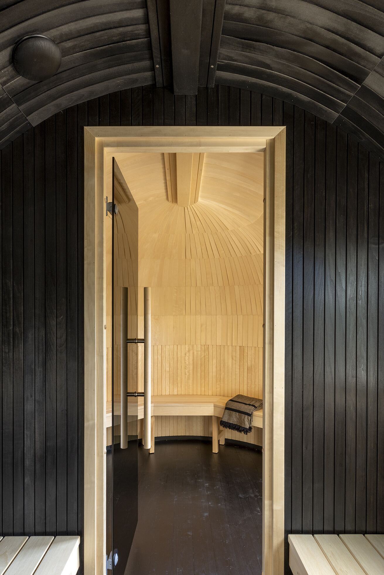 Doorway from the dark outer chamber into the pale-wood inner sauna
