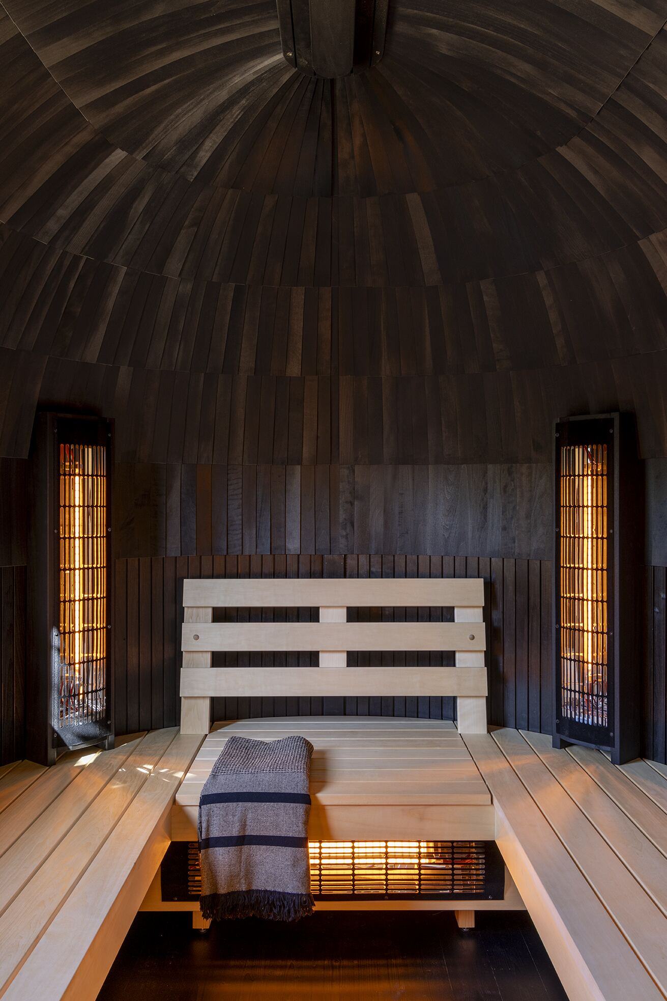Interior of the infrared sauna with domed black timber ceiling and warm-glowing panels