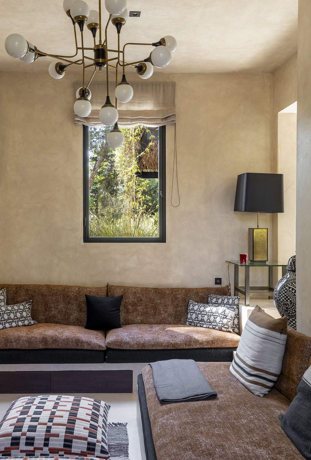 Corner of the TV room with sofa, window onto the garden and black lampshade